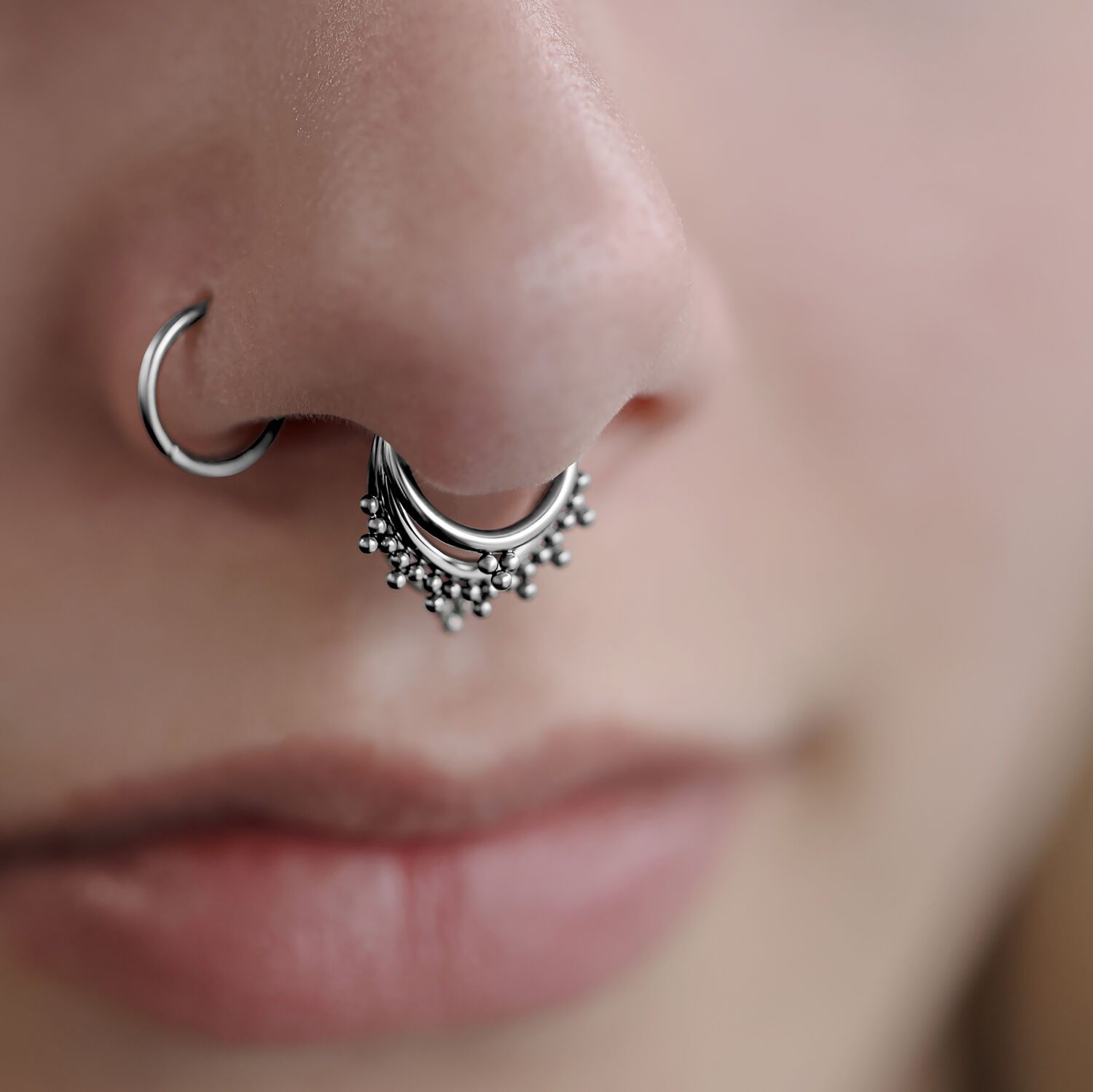 Gros plan sur un Triple Oriental Clicker en argent dans le septum d'un visage