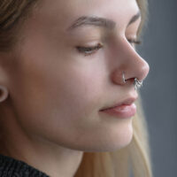 Gros plan d'un Triple Oriental Clicker en argent dans le septum d'une personne