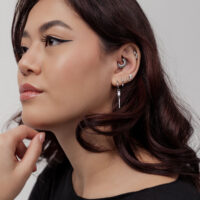 Femme avec plusieurs piercings d'oreilles et de nez en argent, clicker de septum en forme de rayons de soleil