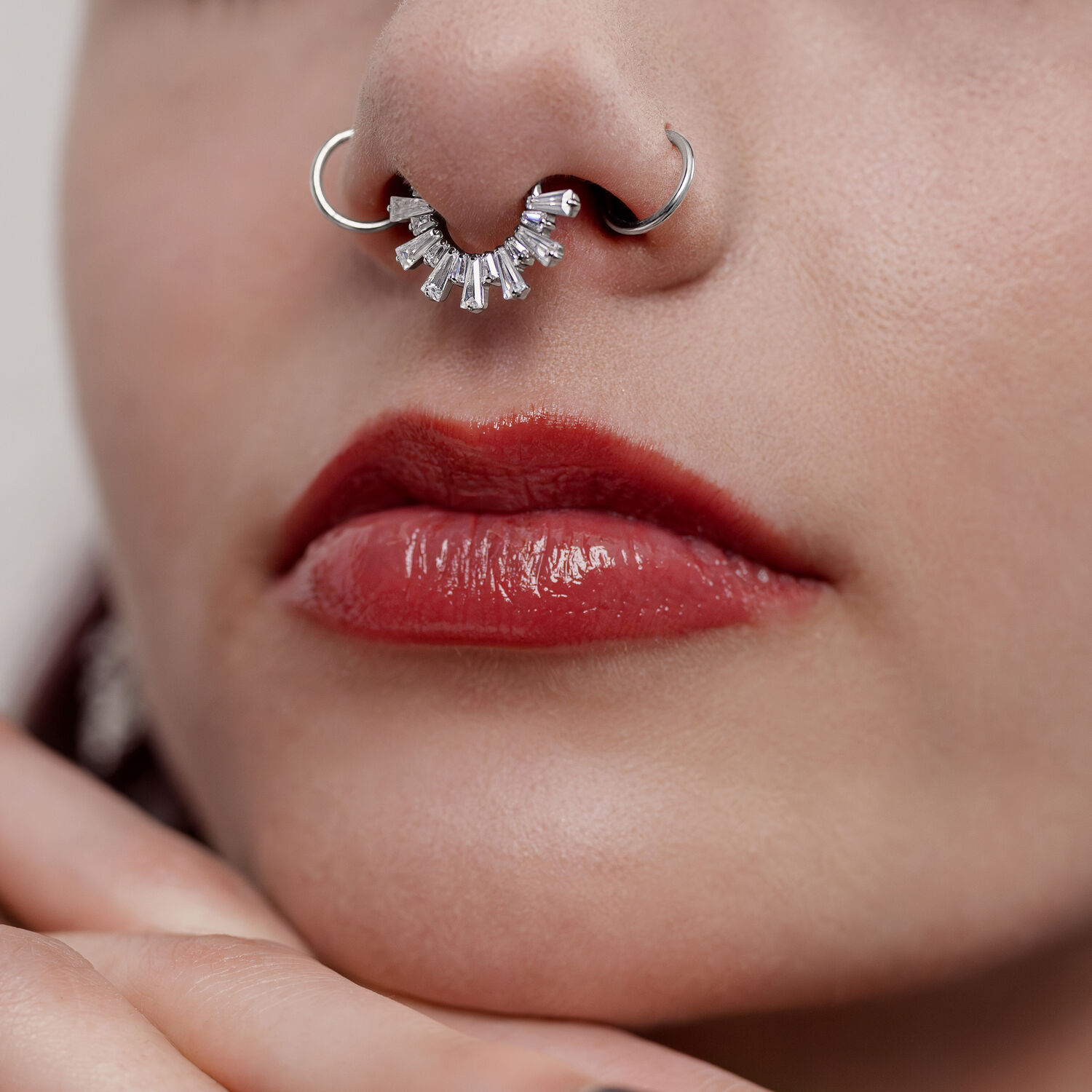 Clicker de septum en cristal argenté Gros plan d'un clicker de septum argenté avec des cristaux dans un nez, lèvres rouges visibles