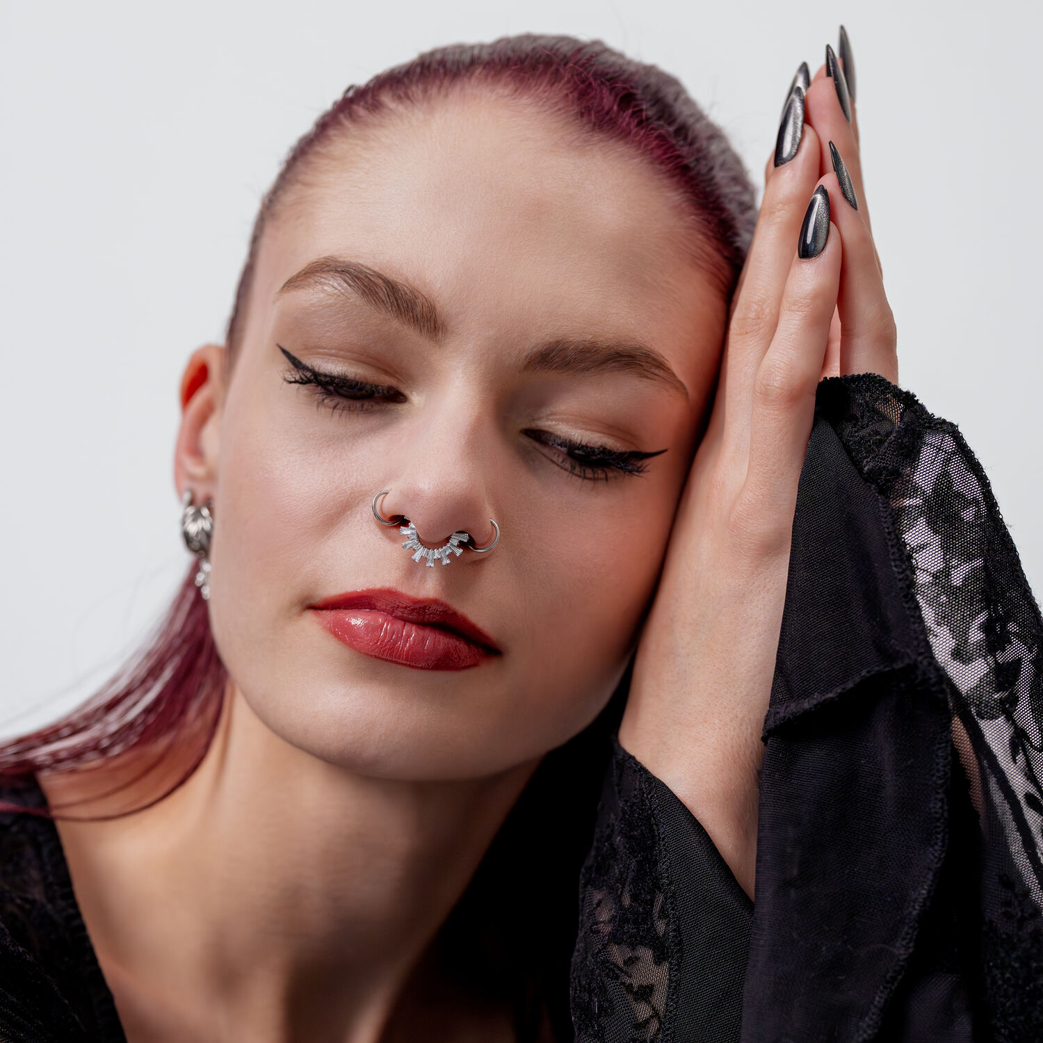 Clicker de Septum en Cristal avec Design Rayons de Soleil Femme aux yeux fermés portant un clicker de septum en cristal argenté, vêtue de noir