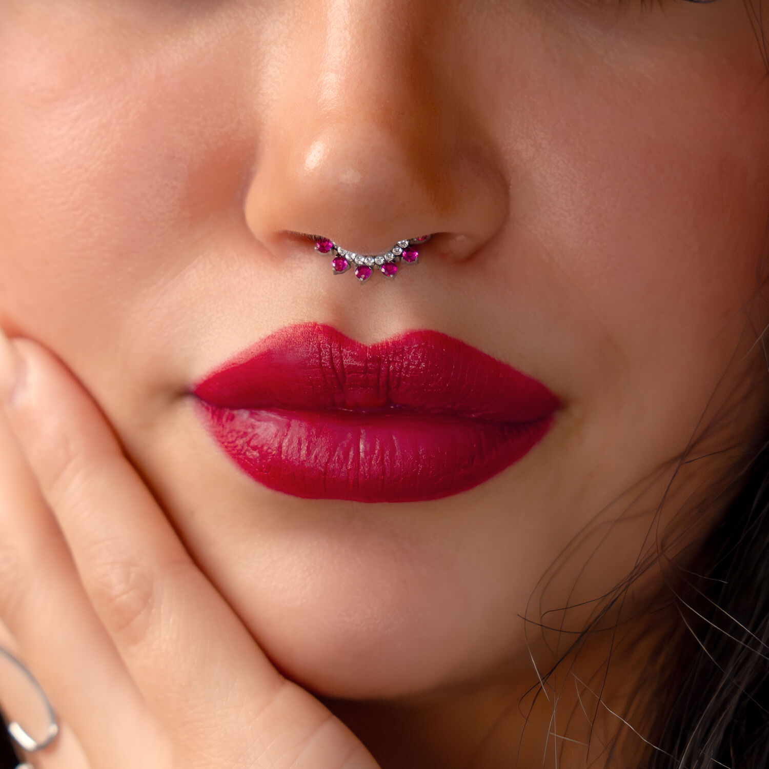 Gros plan d'un visage avec un piercing au septum en argent et cristaux rouges