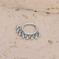 Clicker en titane argenté pour septum avec billes Clicker pour septum argenté avec petites billes sur un fond de pierre texturé