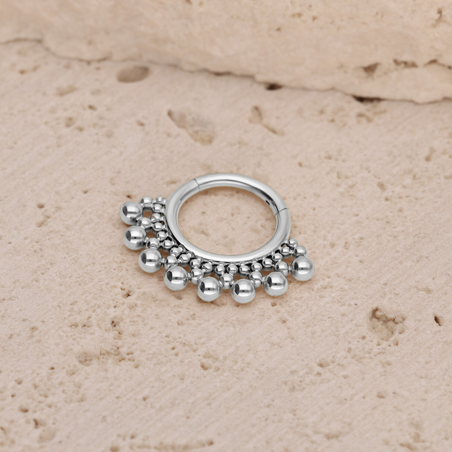 Clicker en titane argenté pour septum avec billes Clicker pour septum argenté avec petites billes sur un fond de pierre texturé