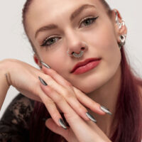 Clicker de septum élégant avec boules décoratives Femme aux cheveux rouges portant un clicker de septum en argent avec des boules décoratives
