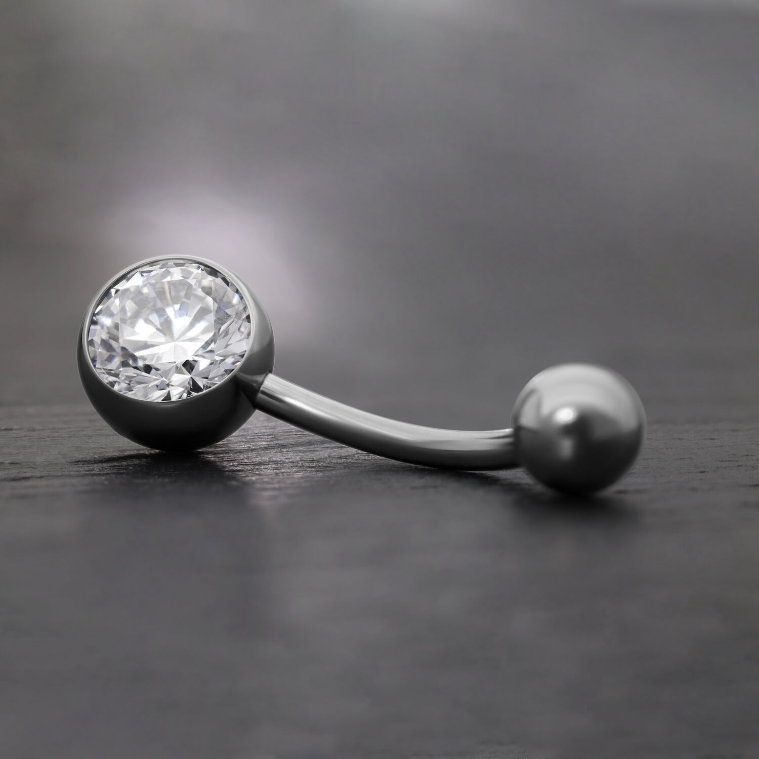 Élégant piercing de nombril avec cristal Banane noire en titane avec cristal clair sur fond gris