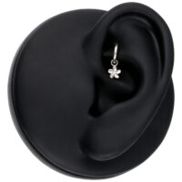 Pendentif Fleur Argenté Piercing Pendentif fleur argenté sur un modèle d'oreille noir, gros plan