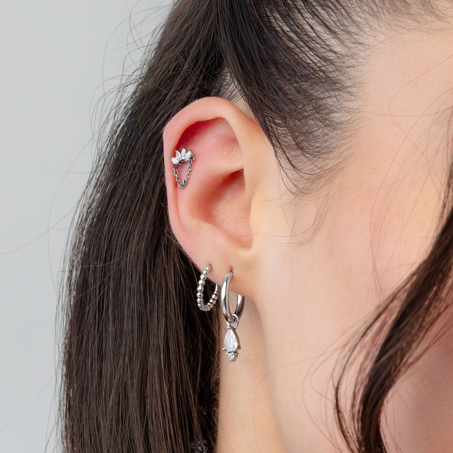Embout de piercing couronne en cristal argenté Oreille avec plusieurs piercings argentés, y compris un embout couronne en cristal clair
