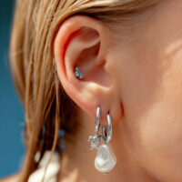 Piercing d'oreille en cristal turquoise avec pendentif Oreille avec créoles argentées et embout en cristal turquoise, gros plan
