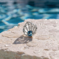 Embout en or blanc en forme de coquillage avec turquoise Embout en or blanc en forme de coquillage avec cristal turquoise sur une pierre mouillée au bord de la piscine