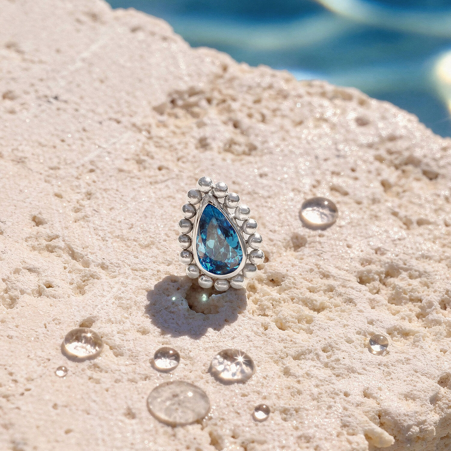 Embout de piercing cristal turquoise Embout en cristal turquoise sur une surface de pierre claire avec des gouttes d'eau
