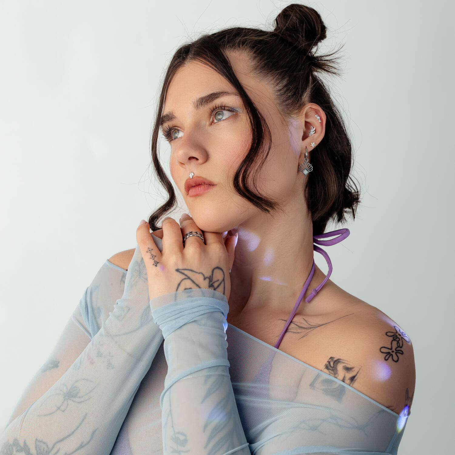 Femme avec top en mesh bleu et motif tatouage sur fond blanc