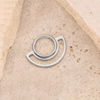 Clicker anneau en argent sur fond de pierre beige, design circulaire