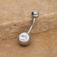 Banane de nombril en titane avec cristal Banane de nombril en argent avec cristal clair sur pierre beige